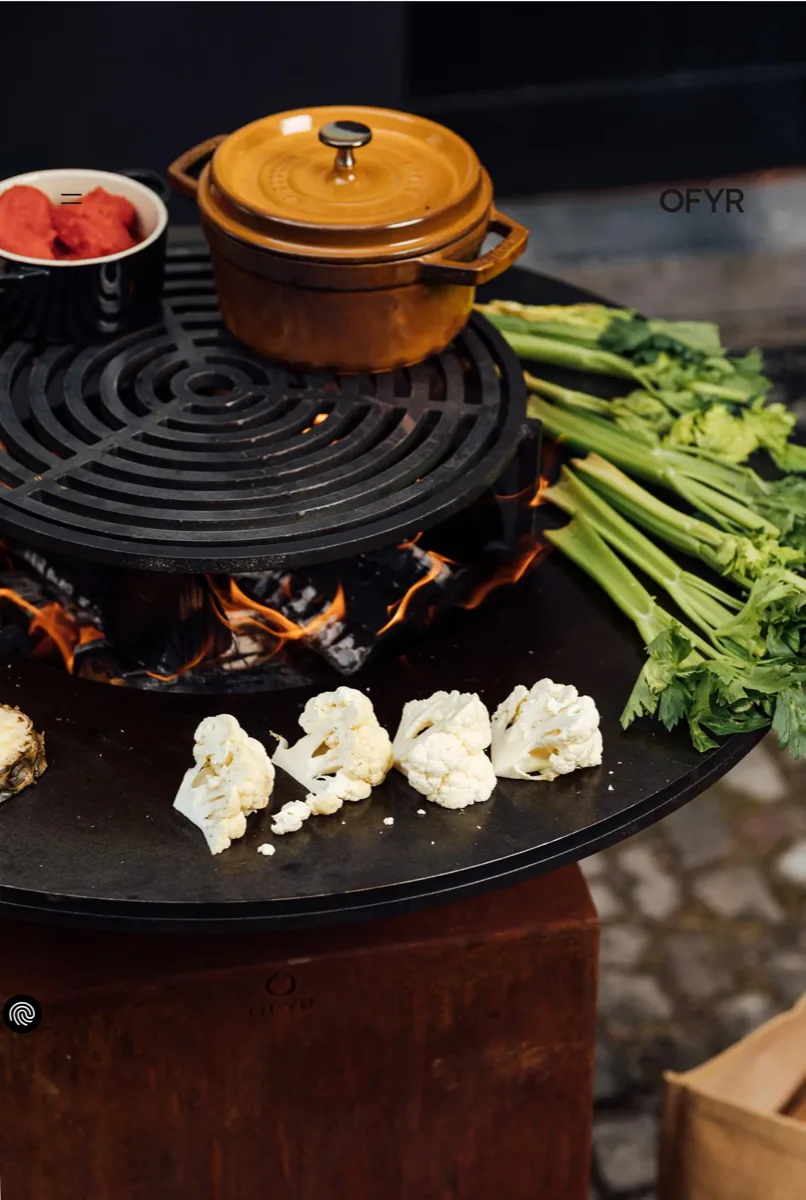 OFYR Classic+ plancha fire pit in Corten steel with vegetables and a Dutch oven cooking